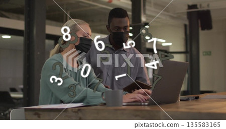 Working masked coworkers analyzing data in open office with laptop, tablet, coffee mug papers 135583165