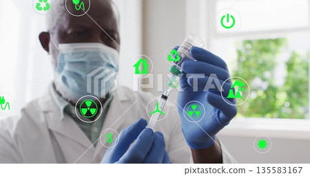 Gloved masked doctor drawing COVID-19 vaccine into syringe at clinic desk, with green icons 135583167