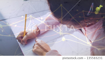 Writing student leaning over notebook on desk at home study, with pencil laptop and graph overlay Writing student leaning over notebook on desk at home study, with pencil laptop and graph overlay 135583231