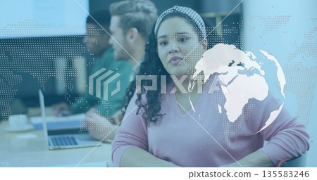 Sitting Hispanic woman in pink sweater listening at conference table, laptops, globe overlay Sitting Hispanic woman in pink sweater listening at conference table, laptops, globe overlay 135583246