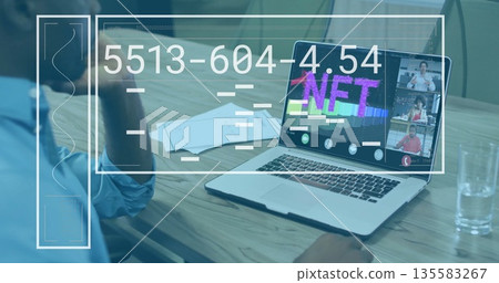 Adult male studying NFT graphic on laptop at conference table, with documents and UI overlays 135583267