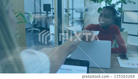 Receiving printed documents from coworker, woman wearing red turtleneck at office desk, copy space 135583268