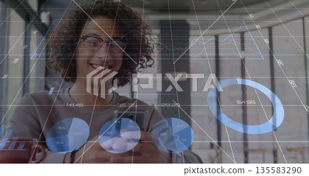 Smiling man looking down at smartphone in coworking space, with data overlays and coffee mug Smiling man looking down at smartphone in coworking space, with data overlays and coffee mug 135583290