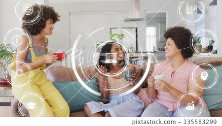 Chatting three friends holding mugs around sofa in bright living room, with digital interface theme Chatting three friends holding mugs around sofa in bright living room, with digital interface theme 135583299