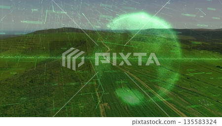 Displaying neon-green scanning sphere over farmland with grid lines, data and winding dirt road 135583324