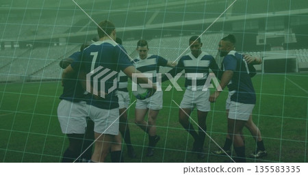 Huddling seven athletes wearing striped jerseys on grass pitch in empty stadium, with rugby ball 135583335