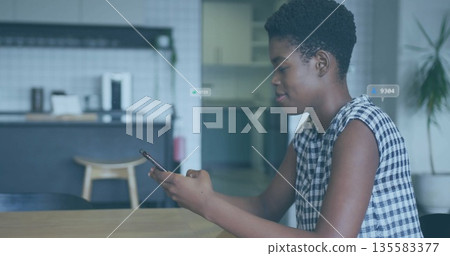 Scrolling woman in checkered top tapping smartphone at kitchen table, copy space 135583377
