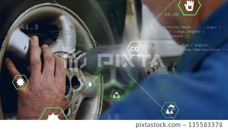 Tightening lug nuts mechanic in blue uniform using impact wrench on wheel in garage, code graphics 135583378