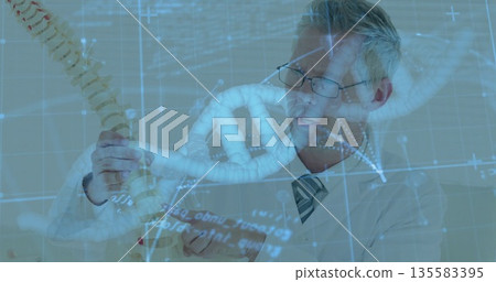 Examining scientist in lab coat holding spine and DNA models in lab, with holographic data Examining scientist in lab coat holding spine and DNA models in lab, with holographic data 135583395