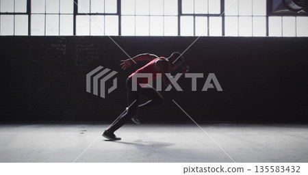 Launching male athlete sprinting across warehouse floor, with red sports top, black tights Launching male athlete sprinting across warehouse floor, with red sports top, black tights 135583432
