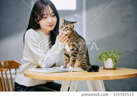 A woman petting a cat on a table 135583523