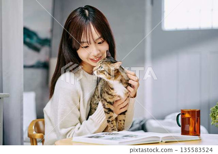 一位女士在桌上撫摸一隻貓。 一位女士在桌上撫摸一隻貓。 135583524