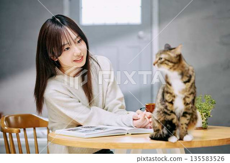 一位女士在桌上撫摸一隻貓。 135583526