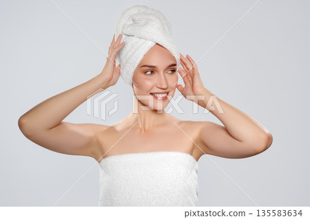 Woman in a towel posing with a towel wrapped around her hair in a clean space Woman in a towel posing with a towel wrapped around her hair in a clean space 135583634