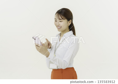 A smiling Japanese woman operating a smartphone on a white background A smiling Japanese woman operating a smartphone on a white background 135583912