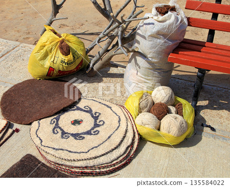 Handmade rugs on the background of sheep and camel wool. Turkmenistan. Ashkhabad market. Handmade rugs on the background of sheep and camel wool. Turkmenistan. Ashkhabad market. 135584022