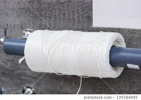 Scene showing cotton thread spool with textured fibers in workshop setting with diffused lighting Scene showing cotton thread spool with textured fibers in workshop setting with diffused lighting 135584095