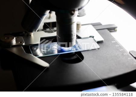 Scientific laboratory setting showcasing detailed cell analysis with microscope under lighting Scientific laboratory setting showcasing detailed cell analysis with microscope under lighting 135584118