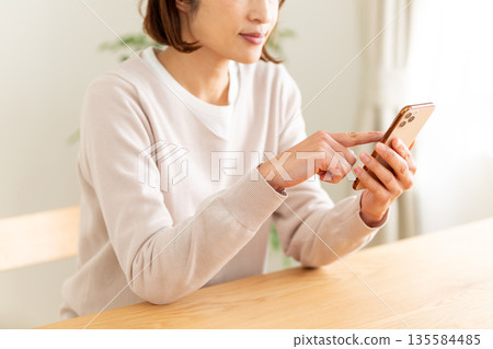 中間女人在房間裡看智能手機 135584485