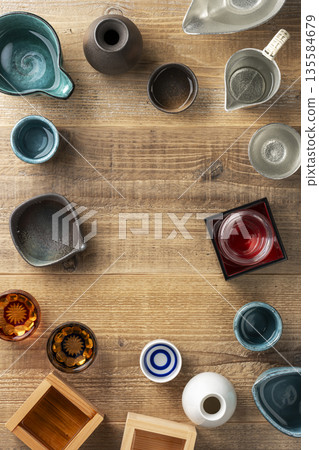 A wooden table background with a Japanese atmosphere, featuring sake cups and sake cups scattered around, and copy space A wooden table background with a Japanese atmosphere, featuring sake cups and sake cups scattered around, and copy space 135584679