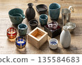 一張充滿日式風格的木桌背景，散落著枡、酒杯等清酒杯。 135584683