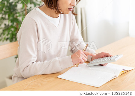 一位中年婦人記帳時憂心忡忡。 135585148