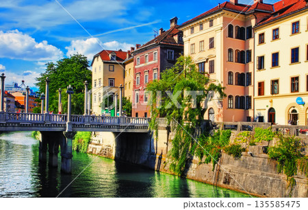 LJUBLJANA, SLOVENIA - JUNE 28, 2014: Old town embankment in Ljubljana. Ljubljana is the business and cultural center of the country. LJUBLJANA, SLOVENIA - JUNE 28, 2014: Old town embankment in Ljubljana. Ljubljana is the business and cultural center of the country. 135585475