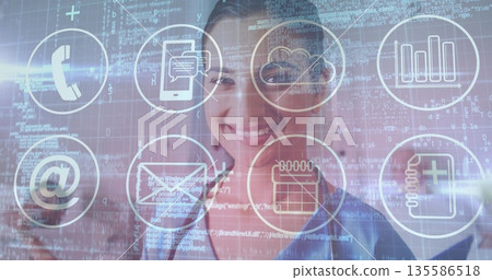Smiling Indian woman in blue shirt displaying telephone, cloud, chat icons with code in office Smiling Indian woman in blue shirt displaying telephone, cloud, chat icons with code in office 135586518