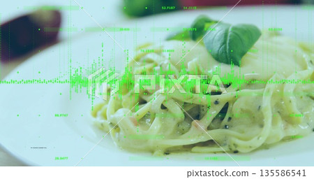 Displaying fettuccine in creamy sauce on plate in dining room, with basil leaf and data overlay 135586541