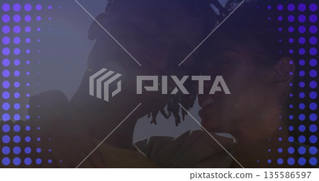 Leaning heads together couple wearing light jacket and t-shirt under clear sky, purple dot overlay 135586597