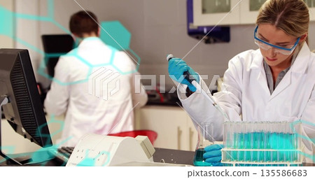 Pipetting scientist moving blue solution into test tubes in lab with gloves and goggles, copy space Pipetting scientist moving blue solution into test tubes in lab with gloves and goggles, copy space 135586683