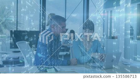 Coworkers wearing business casual reviewing charts, pointing at silver laptop in office, data theme Coworkers wearing business casual reviewing charts, pointing at silver laptop in office, data theme 135586713