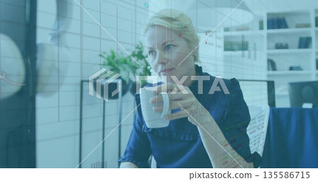 Holding white coffee mug, executive in blouse reviewing metrics in office, with chart overlay Holding white coffee mug, executive in blouse reviewing metrics in office, with chart overlay 135586715
