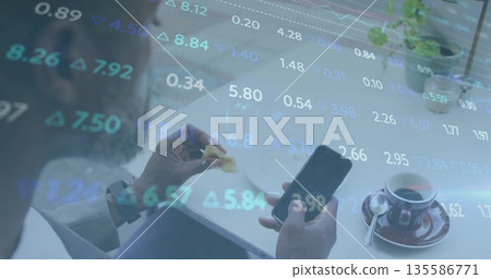 Businessman wearing suit holding smartphone and pastry at cafe table, with stock data overlay Businessman wearing suit holding smartphone and pastry at cafe table, with stock data overlay 135586771
