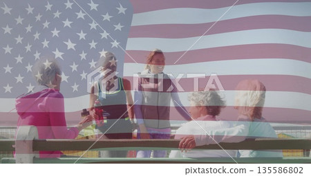 Chatting five women wearing activewear on wooden pier bench by railing and holding water bottles 135586802