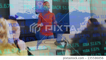 Gesturing presenter in red top and headscarf explaining financial data in boardroom, with laptops Gesturing presenter in red top and headscarf explaining financial data in boardroom, with laptops 135586856