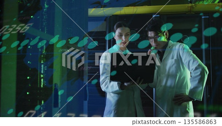 Researchers in lab coats using laptop in server room, with server racks and holographic projections Researchers in lab coats using laptop in server room, with server racks and holographic projections 135586863