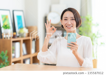 A middle-aged woman watching a smartphone in the living room A middle-aged woman watching a smartphone in the living room 135587012