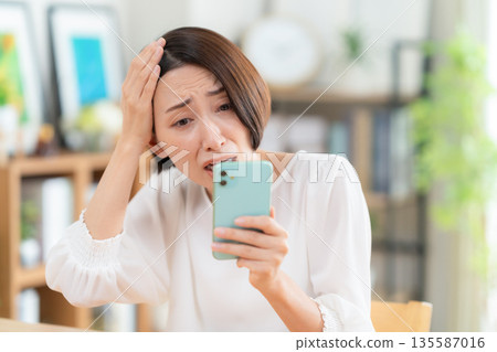 一名中年婦女在客廳裡看著智能手機 135587016