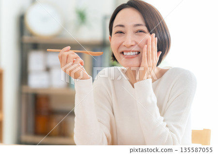 Middle-aged woman eating in the living room 135587055