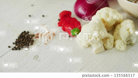 Showing cauliflower florets, pepper and onion slices, translucent social icons on table, copy space 135588317