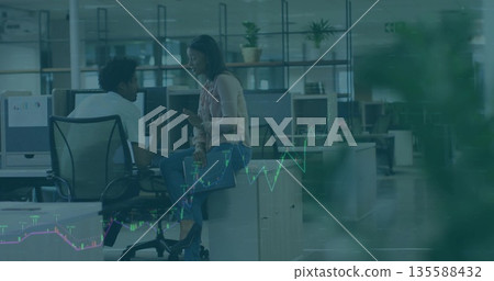 Discussing man and woman in business attire at open-plan office with chart overlay 135588432