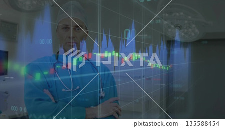 Standing mature male surgeon crossing arms, viewing superimposed financial charts in operating room 135588454