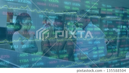Finance team monitoring stock tickers on monitors at office table in suits, with digital overlay 135588504