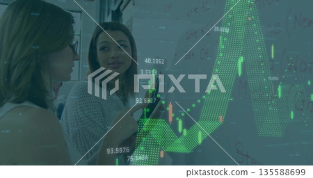 Pointing female colleagues analyzing financial chart overlay on whiteboard, with marker and tablet 135588699