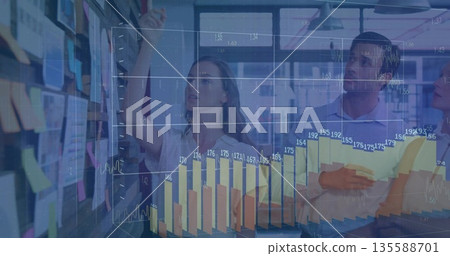 Team in business attire examining sticky notes holding notebook in office, digital charts overlay Team in business attire examining sticky notes holding notebook in office, digital charts overlay 135588701