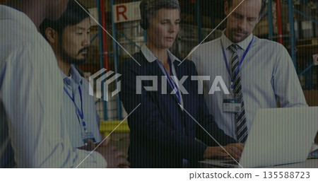Reviewing inventory logistics team analyzing stock in warehouse, with laptop, racks and boxes 135588723