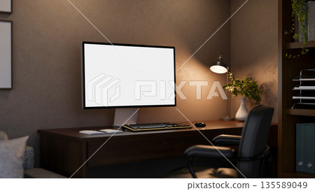Blank screen computer under lamp light on wooden table with leather swivel chair in a dim lit room. 135589049