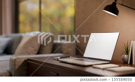White screen laptop and books under lamp light on wooden table aside sofa in a modern living room 135589050