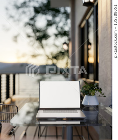 White screen laptop and potted plants on glass table at wooden floor balcony or terrace of a house. 135589051